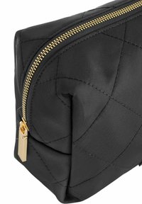 Czarny pikowany worek tekstylny z złotym suwakiem i okuciami. Posiada gładką teksturę i zakrzywiony kształt, zaprojektowany do przenoszenia małych przedmiotów.