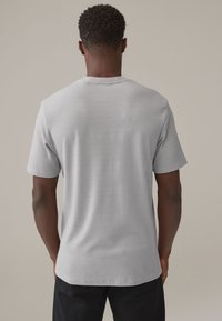 Graues kurzärmeliges T-Shirt mit einem strukturierten, horizontalen Streifenmuster. Hergestellt aus weichem Stoff, hat es einen runden Halsausschnitt und eine lockere Passform.