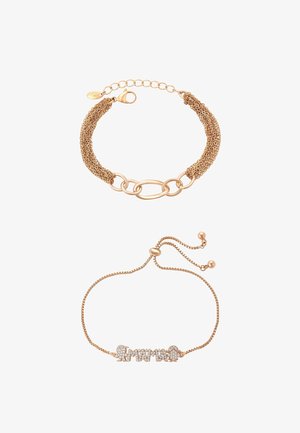 Két aranyszínű karkötő: az egyik láncszemekből és ovális gyűrűkből áll, a másik állítható lánccal és "Amama" felirattal strasszokból.