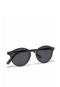 Occhiali da sole ovali neri con lenti scure, sottili bracci neri e un accento metallico minimalista lungo la montatura. Design leggero e moderno.