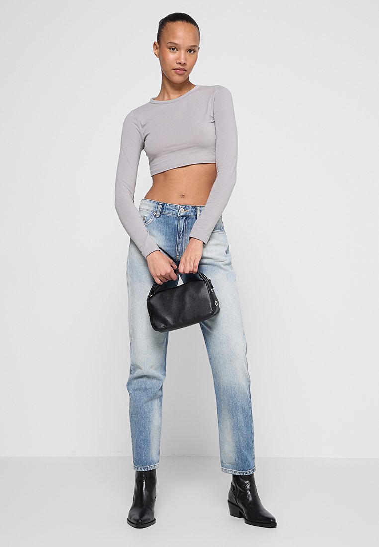 Top corto de manga larga gris, vaqueros holgados azul claro, bolso negro y botas negras hasta el tobillo. Diseño sencillo con colores clásicos.