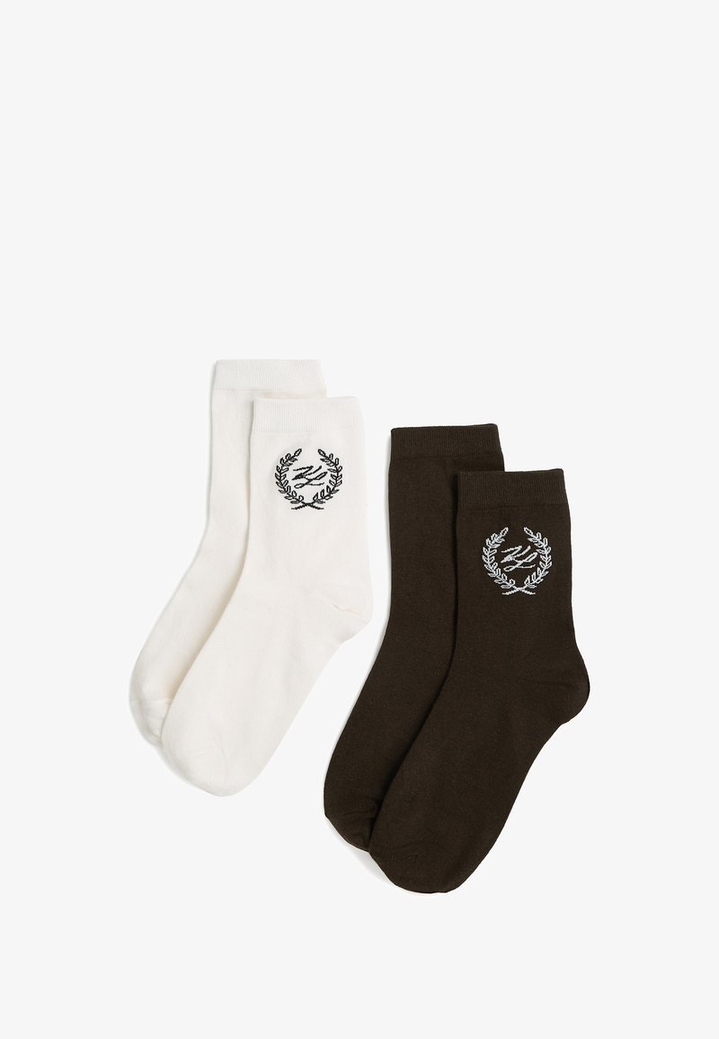 To par sokker i midtkalvslængde, den ene hvide og den anden mørkebrun, hver med et broderet laurbærkranslogo nær kanten.