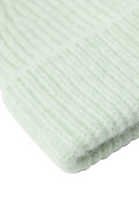 Tessuto a maglia a coste di un verde chiaro, dalla texture morbida, con un bordo ripiegato. Il materiale appare soffice e caldo, adatto per l'abbigliamento invernale.