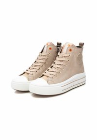 Zapatillas altas beige con suelas de goma blanca. Las características incluyen ojales naranjas, tejido texturizado y un logo en el lateral.