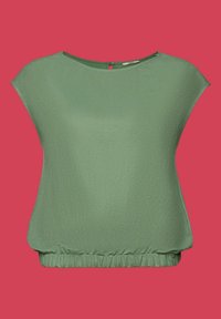 Blouse courte à manches courtes vert clair avec encolure ronde et ourlet froncé élastiqué sur fond rouge uni.