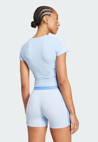 Haut de sport bleu clair à manches courtes, taille côtelée, et shorts assortis avec des rayures latérales bleues. Design élégant et ajusté.