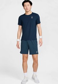 Marinblå sport-t-shirt och matchande shorts i andningsbart material. Har en liten logotyp på tröjan och två framfickor på shortsen.