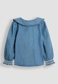 Camicia in denim con maniche lunghe a sbuffo, colletto arricciato e dettagli arricciati ai polsini. Colore azzurro chiaro, texture liscia e vestibilità regolare.