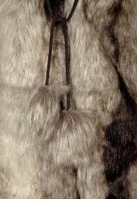 Sztuczny futerko w jasnoszarych i brązowych odcieniach, z teksturowaną powierzchnią, związane ciemno-brązowym sznurkiem, akcentowane puszystymi frędzelkami.