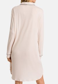 Nightgown lungo a maniche con colletto di un delicato rosa chiaro, caratterizzato da dettagli in piping nero sui polsini e sul collo. Tessuto morbido e liscio.