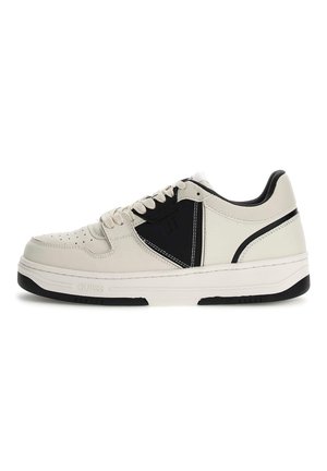 Baskets de sport blanches et noires avec une tige en cuir texturé, un orteil perforé, un panneau latéral contrastant et une semelle en caoutchouc.