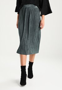 Falda midi plisada en verde azulado oscuro con un diseño texturizado, que presenta una cinturilla elástica ancha y una silueta suave y fluida.