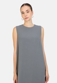 Abito grigio senza maniche con scollo rotondo e vestibilità comoda. Realizzato in tessuto testurizzato, presenta bordi lisci e un design minimale.