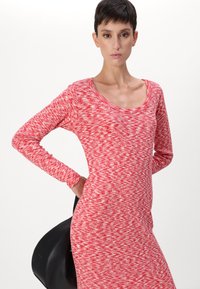 Langärmliges Kleid aus rot-weißem strukturiertem Stoff mit Rundhalsausschnitt, taillierter Form und subtilem Zickzackmuster.