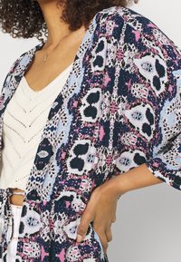 Leichter, gemusterter Kimono in Marineblau, Pink und Weiß mit abstrakten Mustern. Verfügt über weite Ärmel und eine lockere Passform.