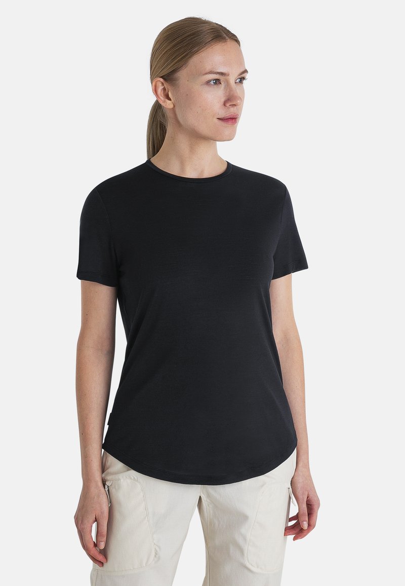 Black short-sleeve shirt with a round neckline and a slightly curved hem, made of soft fabric, worn over light-colored pants.