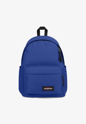 Mochila de tela azul con parte superior redondeada, bolsillo delantero con cremallera, correas ajustables y parche con el logotipo de la marca en la parte inferior del frente.