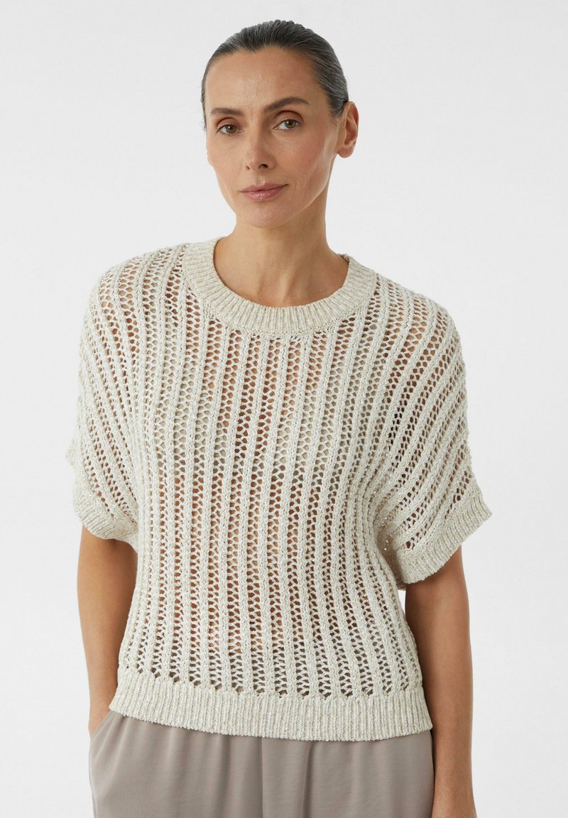 Sweter z dzianiny o luźnym splotu w odcieniu kremowym, z krótkimi rękawami i ściągaczem przy dekolcie. Ma poziome paski i swobodny krój.