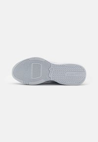 Semelle extérieure d'une basket blanche montrant des motifs de grip texturés, des rainures de flexion et le mot "CALTERRAMAX" embossé sur la semelle.