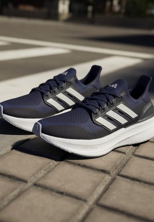 Marineblau sportive Schuhe mit Mesh-Obermaterial, weißem Drei-Streifen-Design, strukturiertem Oberflächen, gepolsterter Sohle und grauen Akzenten an der Ferse.