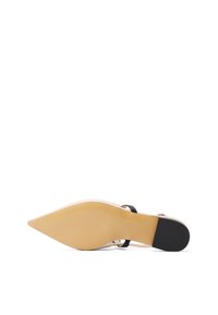 Scarpa con tacco alto a punta, con parte superiore beige, fibbia nera alla caviglia e suola beige. La parte inferiore presenta un'area in gomma nera texture.