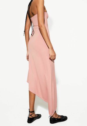 Rosa, off-shoulder midiklänning med asymmetrisk fåll och slät textur, i kombination med svarta snörskor för kontrast.