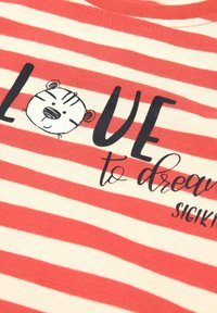 Red and cream striped t-shirt featuring black text "LOVE to dream" with a cartoon bear face graphic on the front.