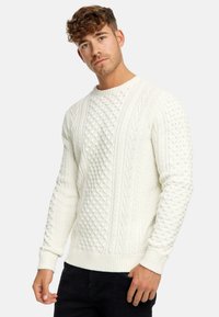 Weißer Strickpullover mit strukturiertem Muster, Zöpfen und Knötchen, Rundhalsausschnitt sowie gerippten Bündchen und Saum.