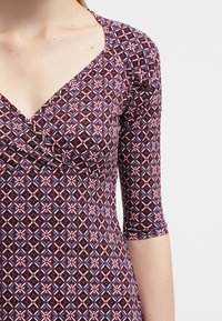 Wrapklänning i mönstrad stretchtyp; har en djup V-ringning, trekvartsärmar och geometrisk design i vinröd, blå och krämfärgad.