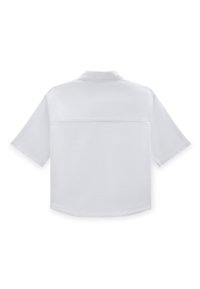 Camisa blanca de manga corta con cuello mao, que presenta una textura suave, dobladillo recto y un detalle en el yugo trasero.