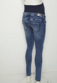 Los jeans skinny de mezclilla azul cuentan con una cintura alta, un ligero desvanecimiento y bolsillos traseros. Están diseñados para una silueta ajustada.