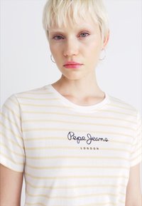 Hvit T-skjorte med gule horisontale striper, rund hals, korte ermer, med marineblå logo-tekst "Pepe Jeans LONDON" på forsiden.
