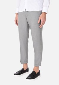 Pantaloni grigi sartoriali con una texture sottile, orli alla francese, abbinati a scarpe slip-on nere con un design perforato.
