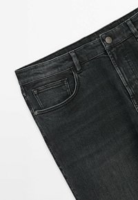 Jean en denim noir, partie supérieure montrant la poche avant, la fermeture à bouton, les passants de ceinture et les détails de couture sur un fond blanc.