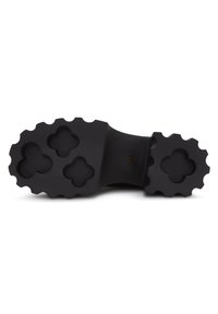 Suola di stivale in gomma nera con un pattern di presa testurizzato, caratterizzata da quattro ritagli a forma di fiore e un design con bordo arrotondato.