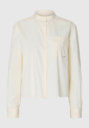 Cream long-sleeve blouse with mandarin collar, front buttons, and a chest pocket featuring small embroidered text.