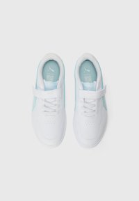 Des baskets blanches avec des accents bleu clair, à lacets à l'avant et une seule bande Velcro, vues d'au-dessus sur un fond blanc uni.