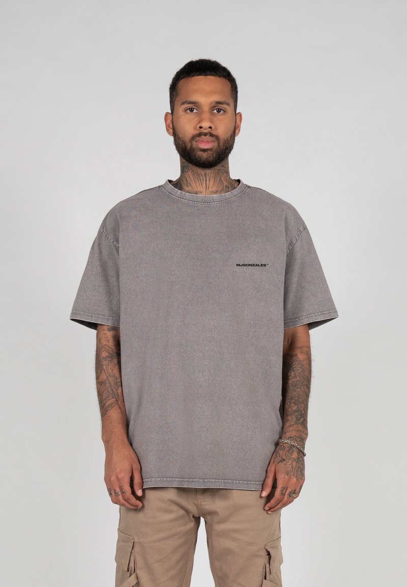 Gray oversized t-shirt in a faded wash, featuring a round neck and short sleeves. Small black logo accent on the left chest area.