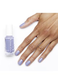 Bottiglia di smalto per unghie lavanda accanto a una mano con unghie ben curate, tutte smaltate dello stesso tono lavanda, su uno sfondo bianco.
