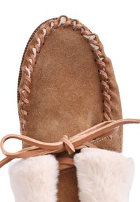 Botte en daim marron avec une tige cousue, des lacets en cuir et une douce doublure en fourrure blanche au niveau du haut. Design à bout rond.