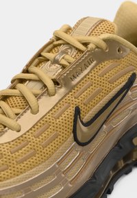 Sárga Nike Max Air sportcipők hálós felsőrésszel, textúrázott díszítésekkel, kontrasztos fekete logóval és látható légpárnázással a talpában.