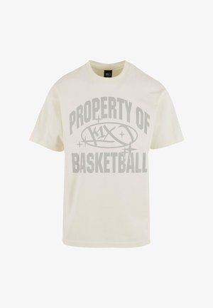 Kreemivärvi puuvillane T-särk, millel on suur hall graafika, kus on kirjas "K1X BASKETBALL" julge, sportlikus fondis. Lühikesed varrukad, ümar kaelus.