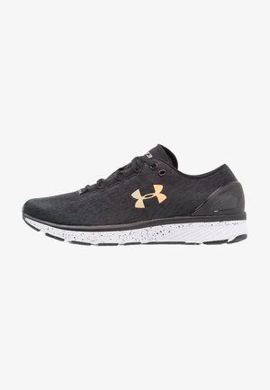 Black athletic shoes with a textured upper, featuring a gold logo, white speckled midsole, and black rubber outsole. Mesh material for breathability.