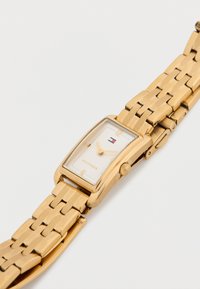 Gold-tone rectangular watch with a white dial, minimalist hour markers, and a metal link bracelet. Features a crown on the side.