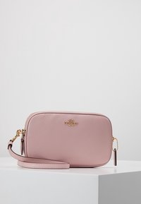 Vaaleanpunainen nahkainen olkalaukku, jossa on tekstuuripinta, kultaiset yksityiskohdat ja irrotettava hihna. Varustettu vetoketjukiinnityksellä ja logokoristeella.