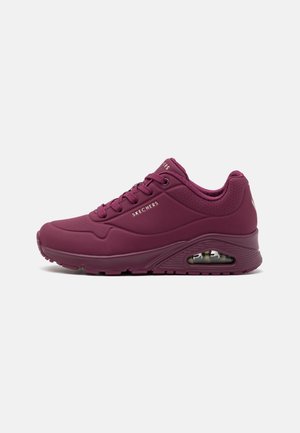 Bordowe buty sportowe Skechers z wiązaniem na sznurówki, oddychającymi perforacjami, wyściełanym kołnierzem i widoczną podeszwą z poduszką powietrzną na białym tle.
