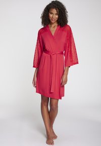 Raudonas chalatas su nėrinių detalėmis trimis ketvirčiais rankovių, minkštos medžiagos, su diržu liemeniuose, ir kelius siekiančiu kirpimu.