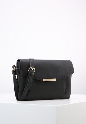 Borsa a tracolla nera in pelle con tracolla regolabile e chiusura rettangolare dorata su un piedistallo bianco.