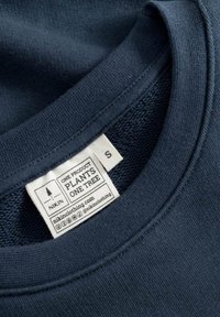 Marineblauwe katoenen T-shirt met ronde hals, voorzien van een label met de tekst "Één product plant één boom" en maat "S." Gladde textuur.
