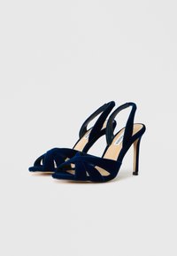 Navy zilas samta augstpapēžu sandales ar siksniņu dizainu, atvērtu purngali un aizdari uz papēža. Gluda tekstūra ar sarežģītiem krusteniskajiem rakstiem.
